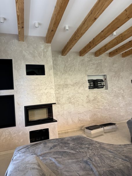 Kreativtechnik – Raumansicht Kreative Wandgestaltung rund um den Kamin, kombiniert mit sichtbaren Holzbalken.